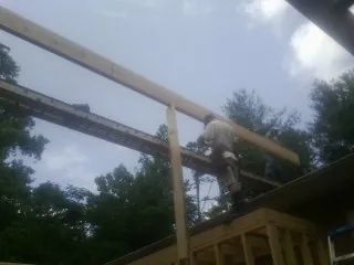 Carpenter setting a ridge beam over a new addition frame — Ice Dam Removal by Roofing Brothers in Newborn