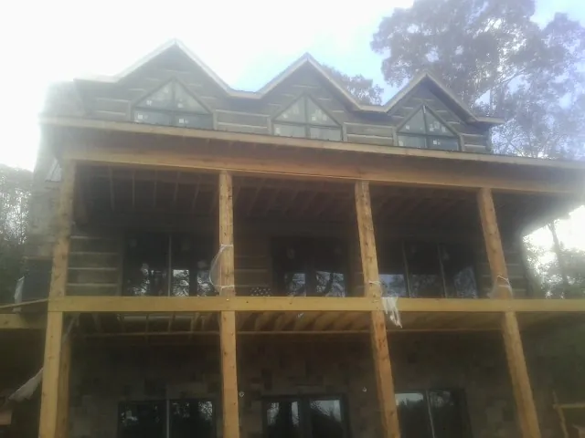 Dormers and porch framing on a large log home under construction — Roof Coating work by our crew in Newborn