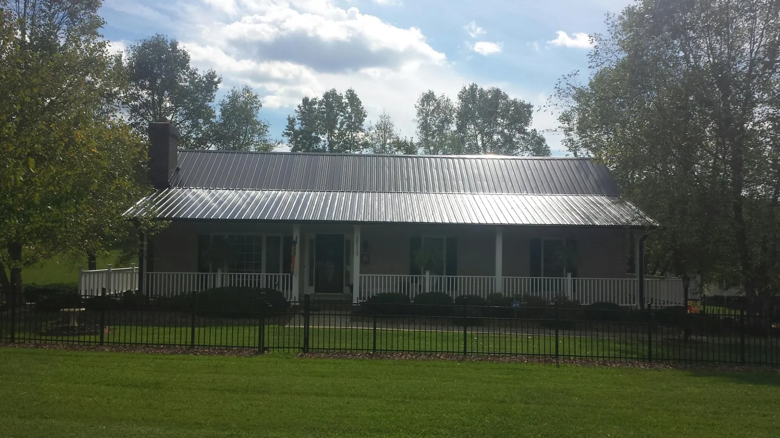 Gray metal roof on a brick ranch with a full width front porch — Gutter Guard Installation work by our crew in Newborn